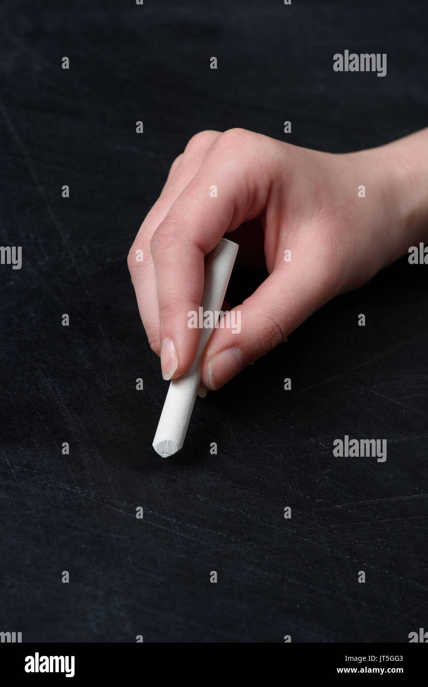 Stretta di mano umana la scrittura con un pezzo di gesso sulla lavagna Foto Stock