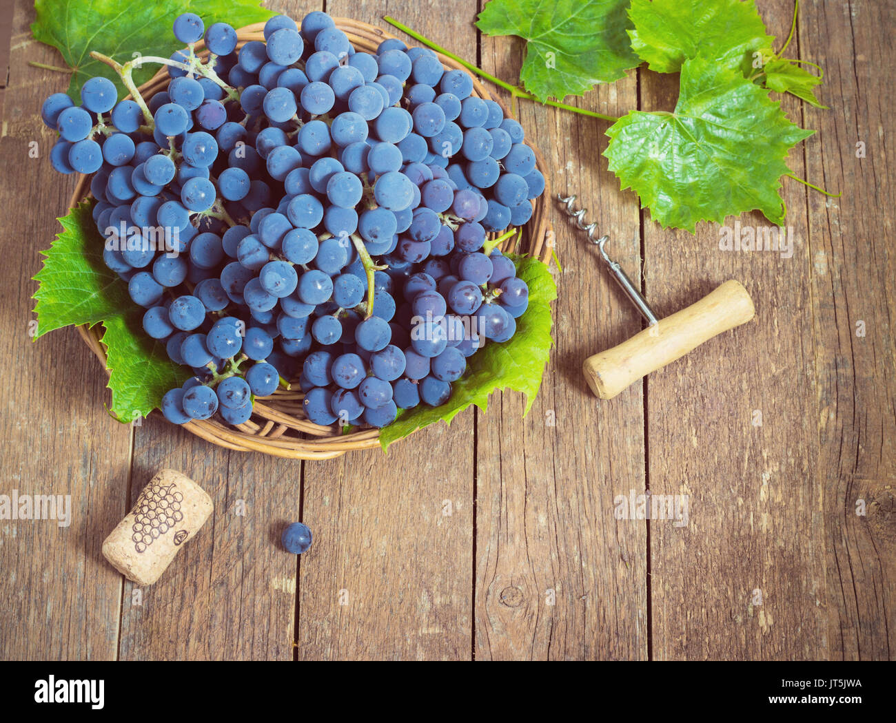 Uva blu in un cesto su uno sfondo di legno tonificante Foto Stock