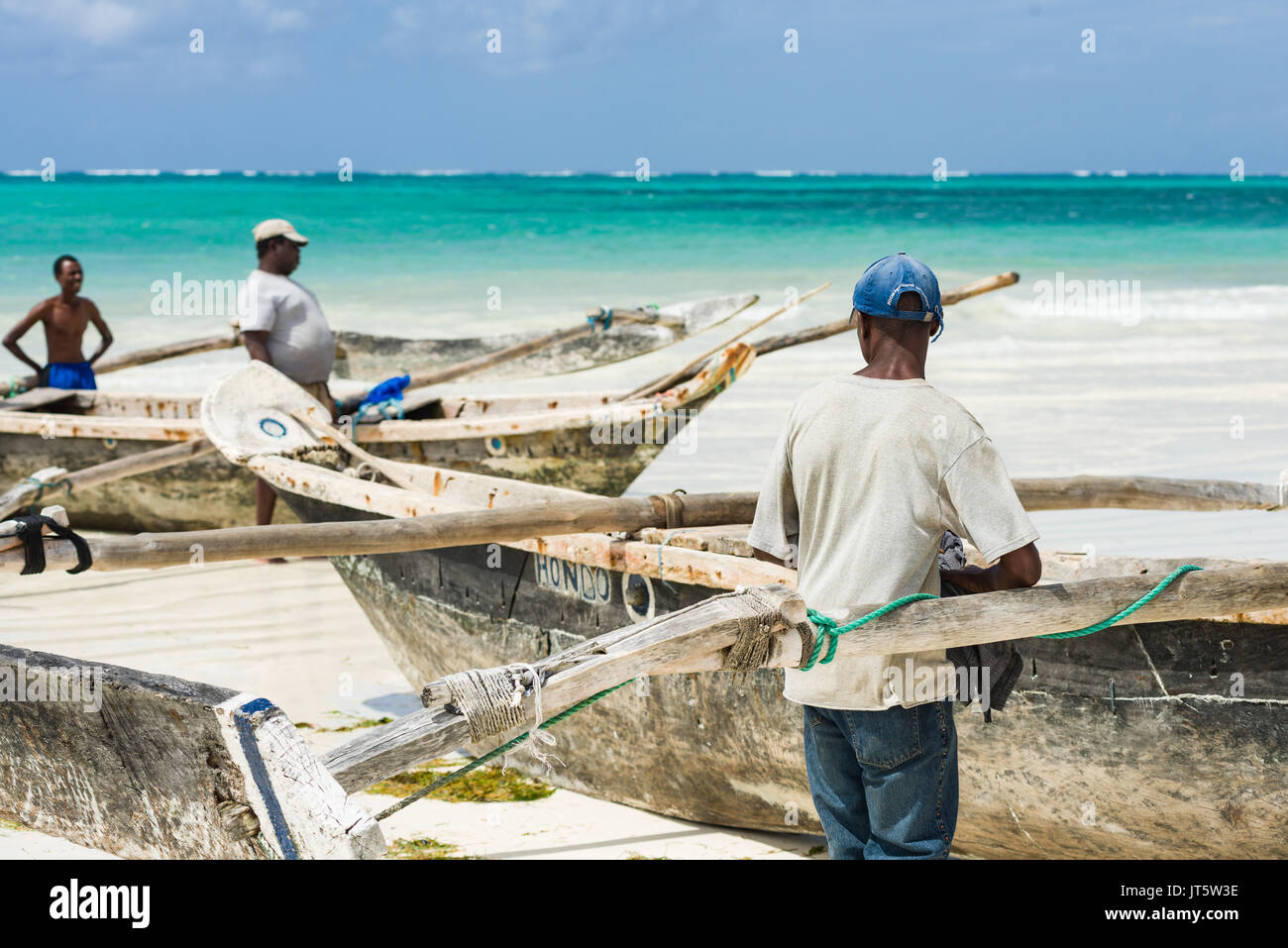 Fisherman attendere per spingere il sambuco tradizionale barca da pesca per l'oceano, la spiaggia di Diani, Kenya Foto Stock