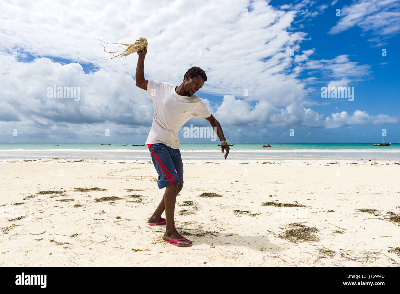 Fisherman tenderises e prepara fresco polpo catturato da lanciarla contro la sabbia della spiaggia, Diani, Kenya Foto Stock