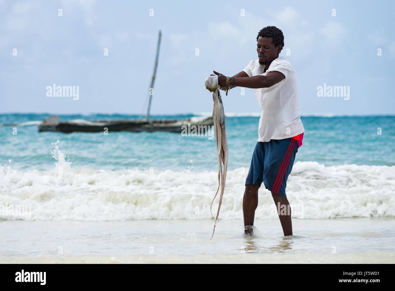 Fisherman lavaggi catturato il polpo in acqua di mare dal litorale, spiaggia di Diani, Kenya Foto Stock