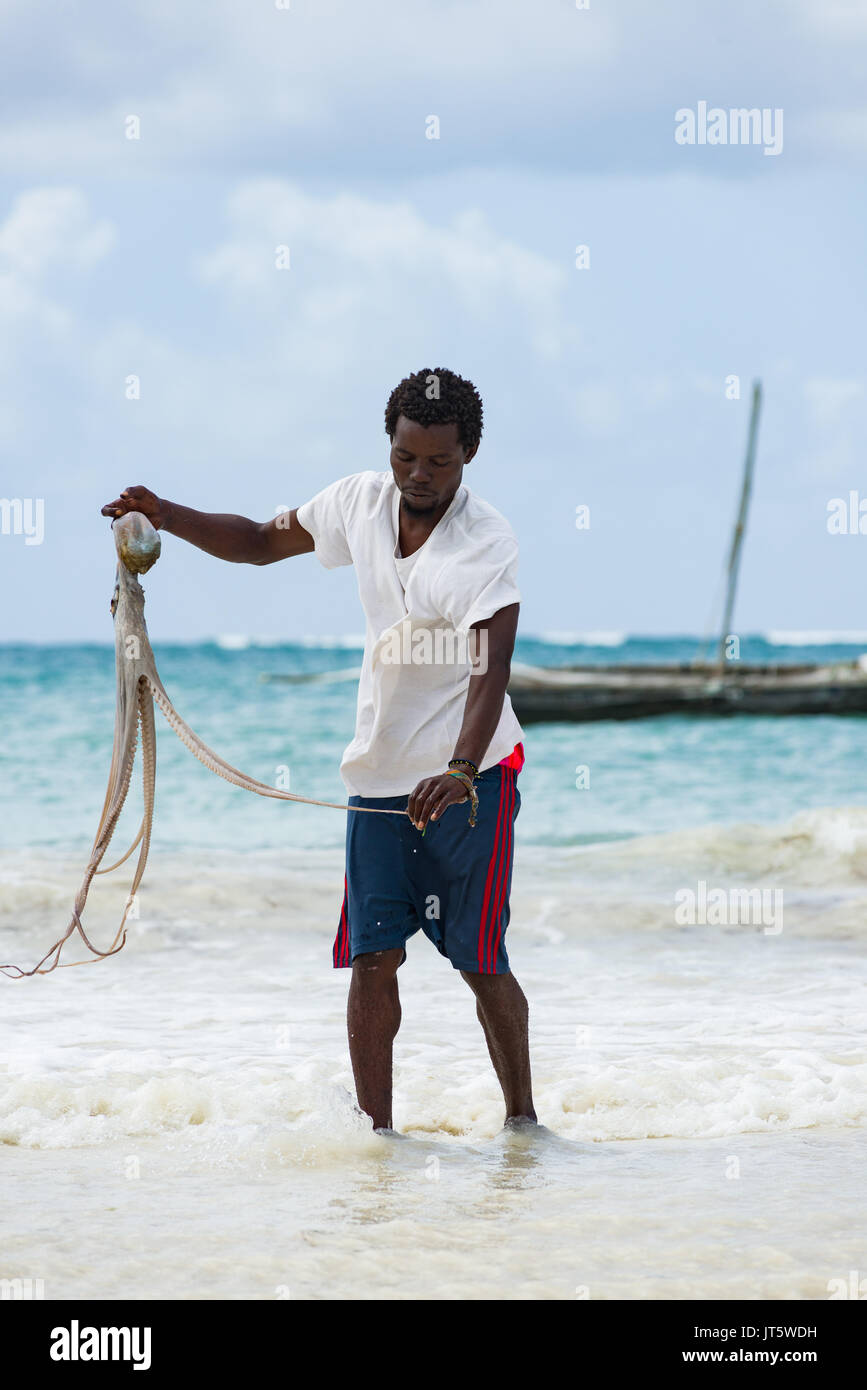 Fisherman lavaggi catturato il polpo in acqua di mare dal litorale, spiaggia di Diani, Kenya Foto Stock