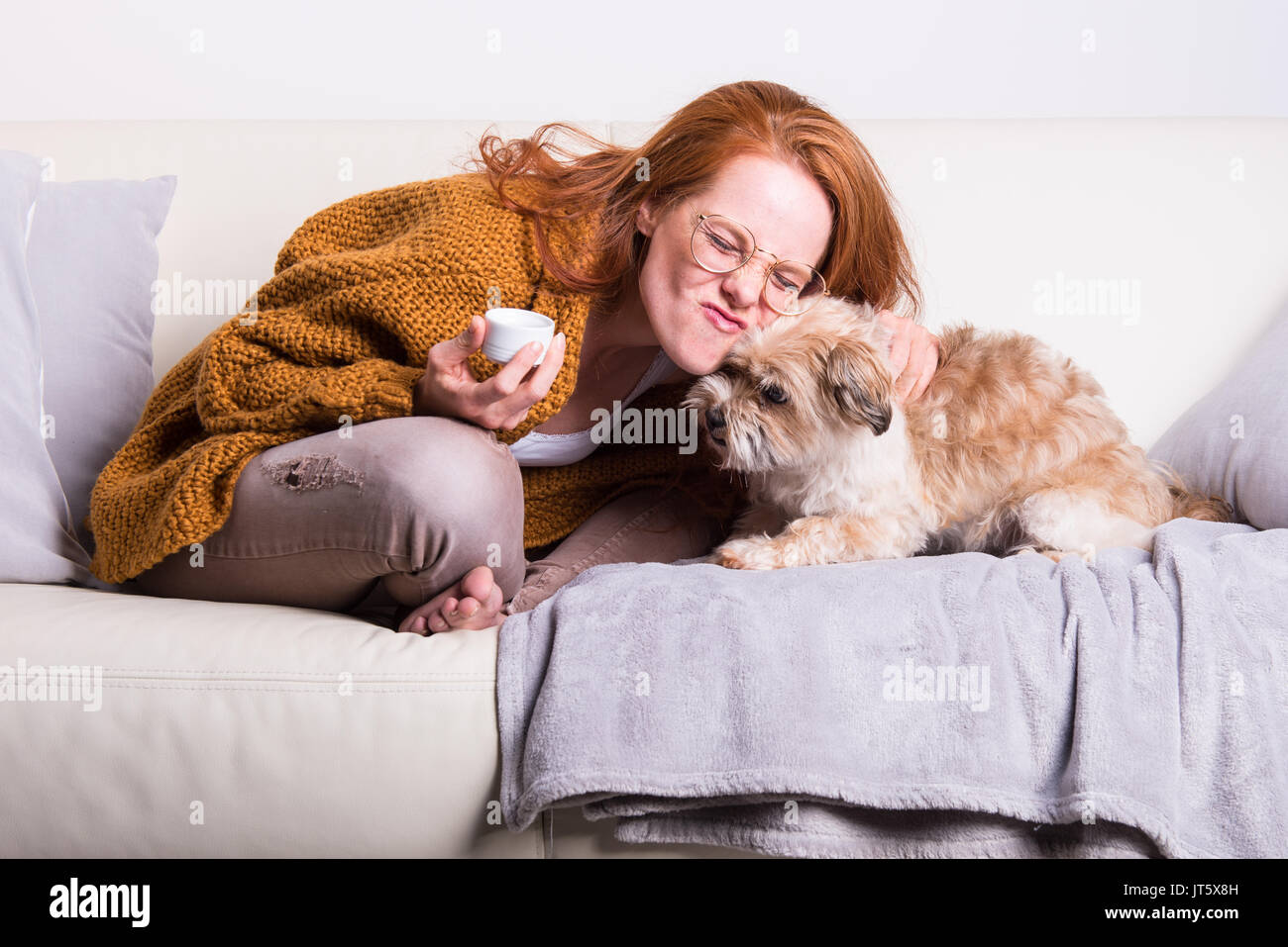 Bella, i capelli rossi donna con maglione arancione si siede con il suo cane Foto Stock