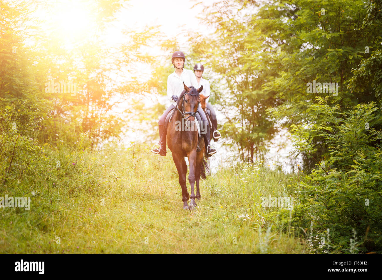 Due rider donna su cavalli andando giù dalla collina. Equestre attività estate sfondo Foto Stock
