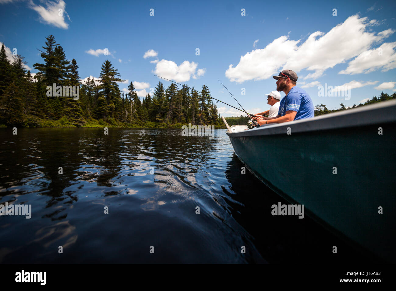 Sun e padre di pesca in un lago calmo nella natura selvaggia da una barca. Foto Stock