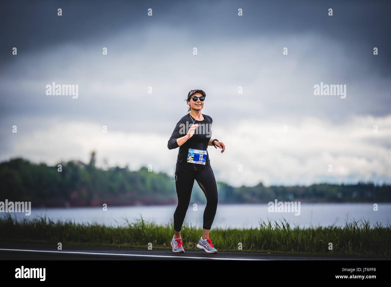 CARLETON, Canada - 4 giugno 2017. Durante la quinta maratona di Carleton in Quebec, Canada. Giovane donna maratoneta a circa 7 km di distanza da sola sulla s Foto Stock