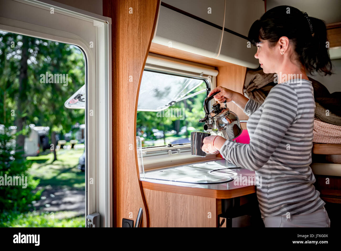 Donna cucinare in camper, camper interni. Vacanza per la famiglia in viaggio, viaggio vacanza in camper, caravan auto vacanza. Foto Stock