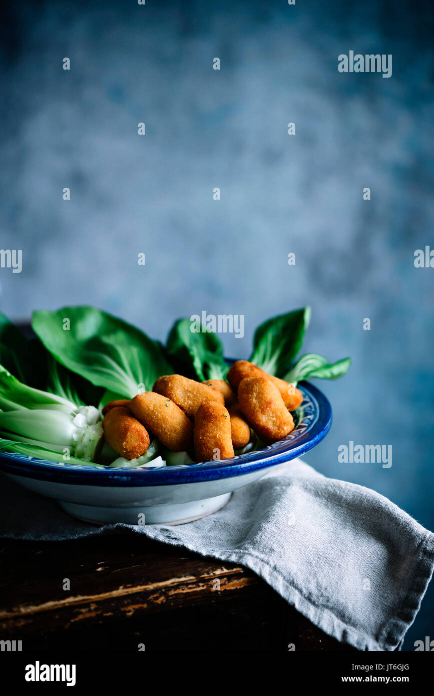 Cavolo cinese Pak Choi su uno sfondo blu con crocchette di patate Foto Stock