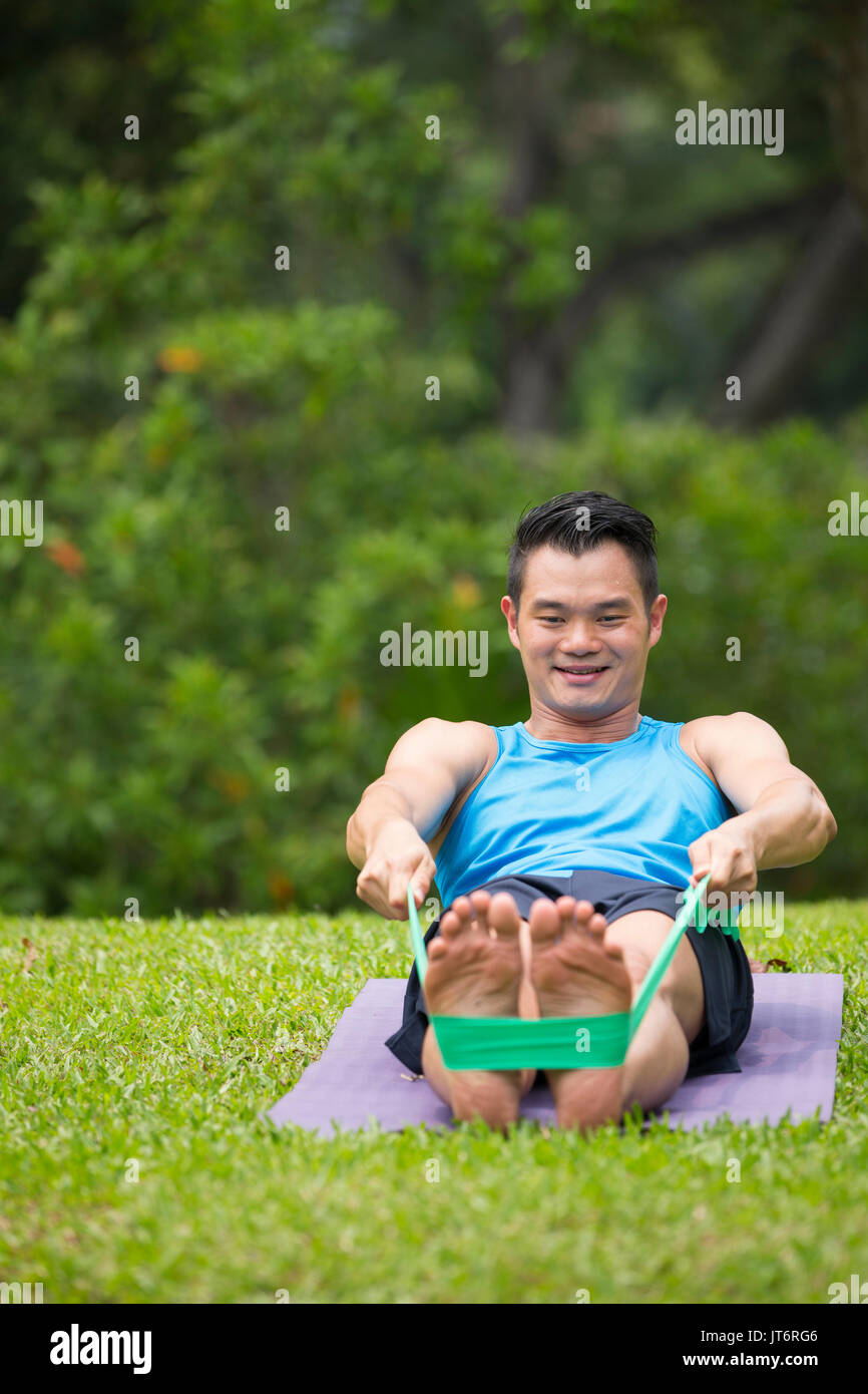 Athletic uomo asiatico esercizio con una banda di resistenza. Azione e uno stile di vita sano concetto. Foto Stock