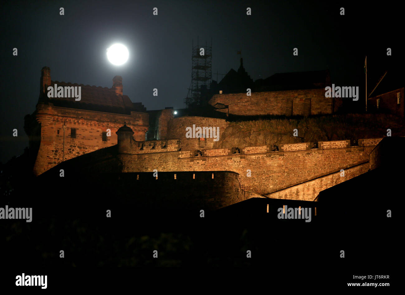 Una luna piena, noto come lo storione Luna nel mese di agosto, sorge dietro al Castello di Edimburgo. Foto Stock