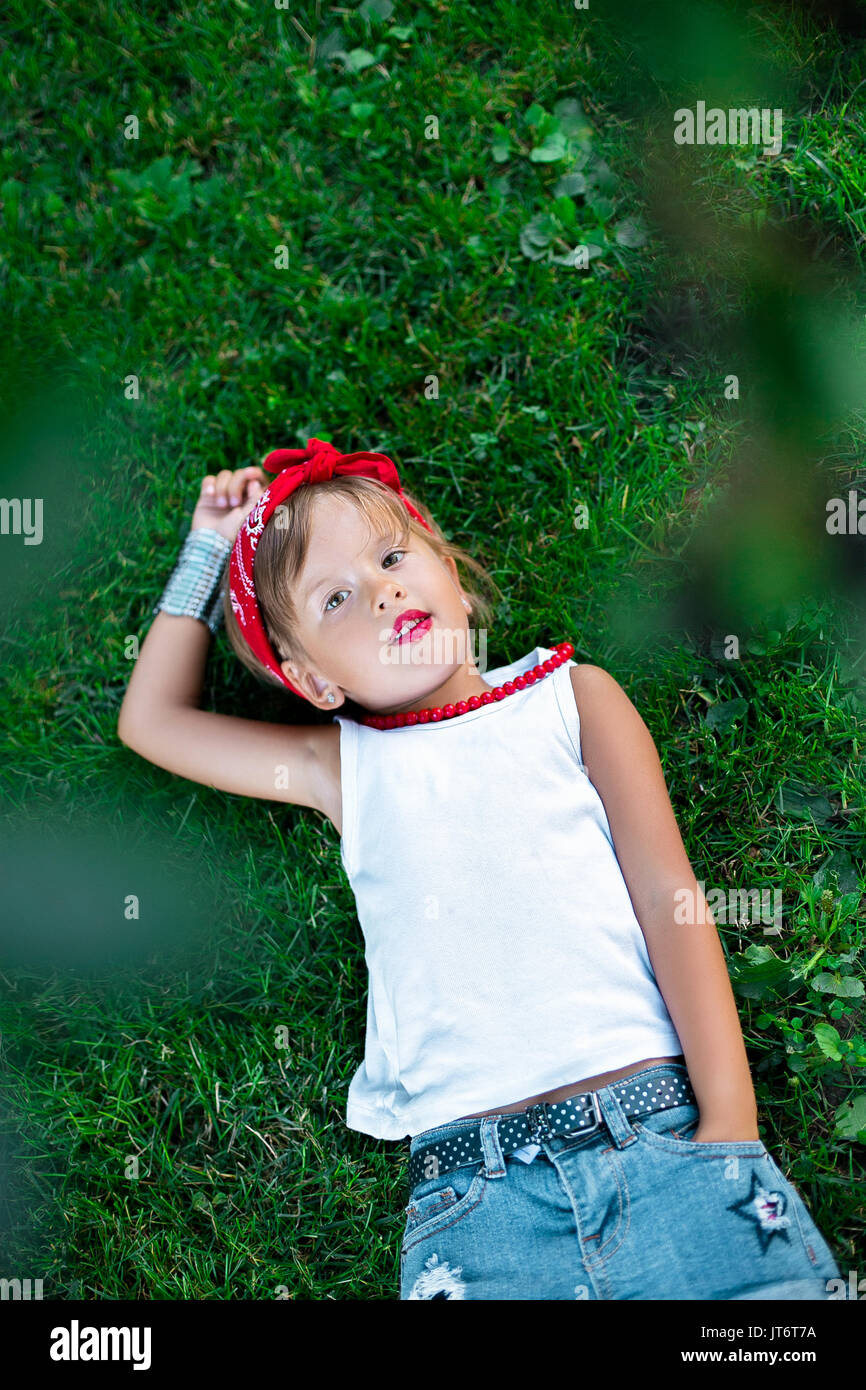 Cool bambina outdoor sdraiati sull erba. Bambino in bianco t shirt