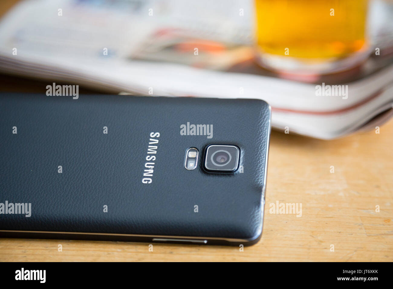 Londra, Regno Unito. Chiusura del logo Samsung e fotocamera su Samsung smartphone nella parte anteriore di una pinta di birra e un quotidiano. Foto Stock