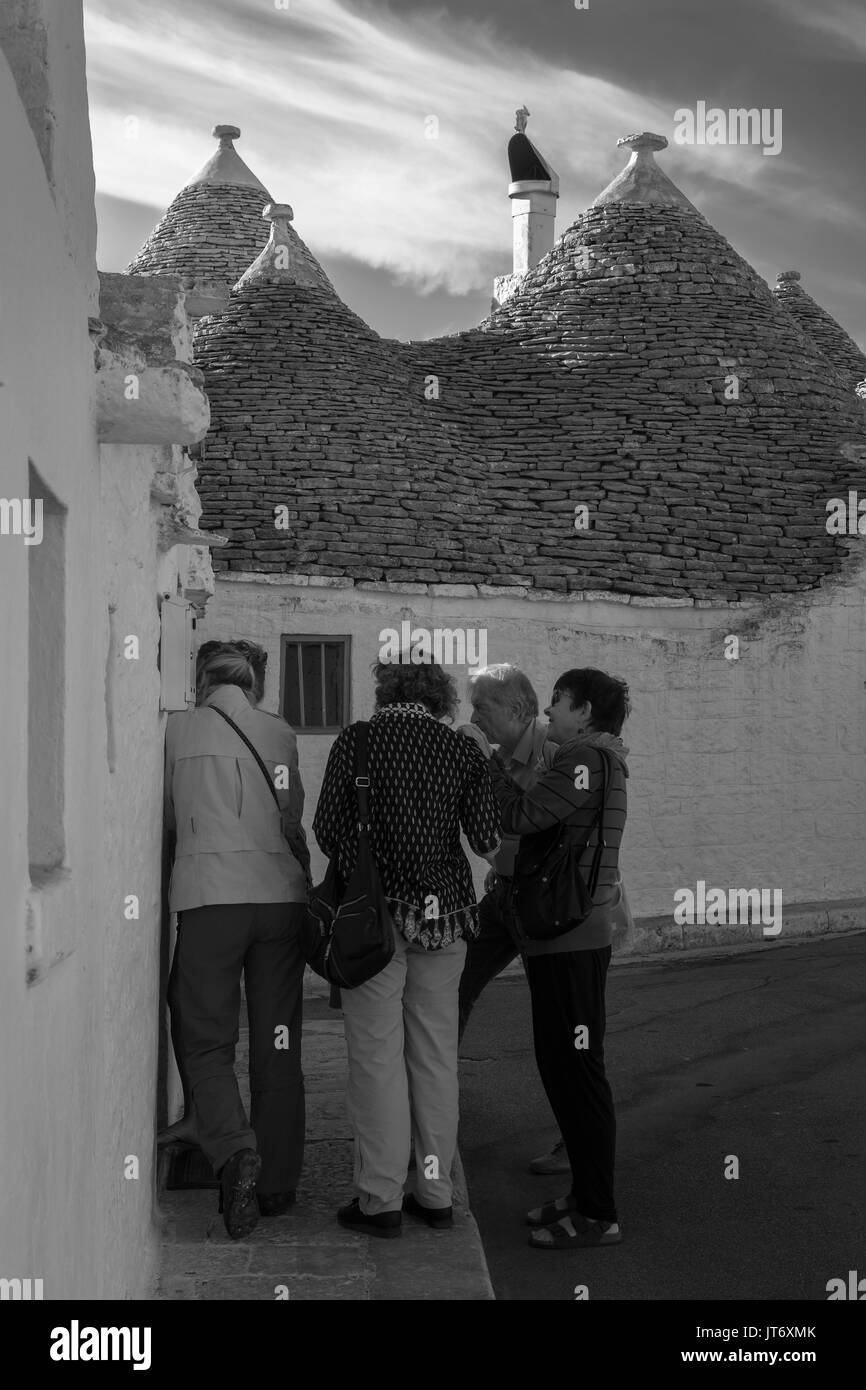 Chiacchierando fuori un trullo su Via Duca degli Abruzzi, Aia piccola, Alberobello, Puglia, Italia: Versione in bianco e nero Foto Stock