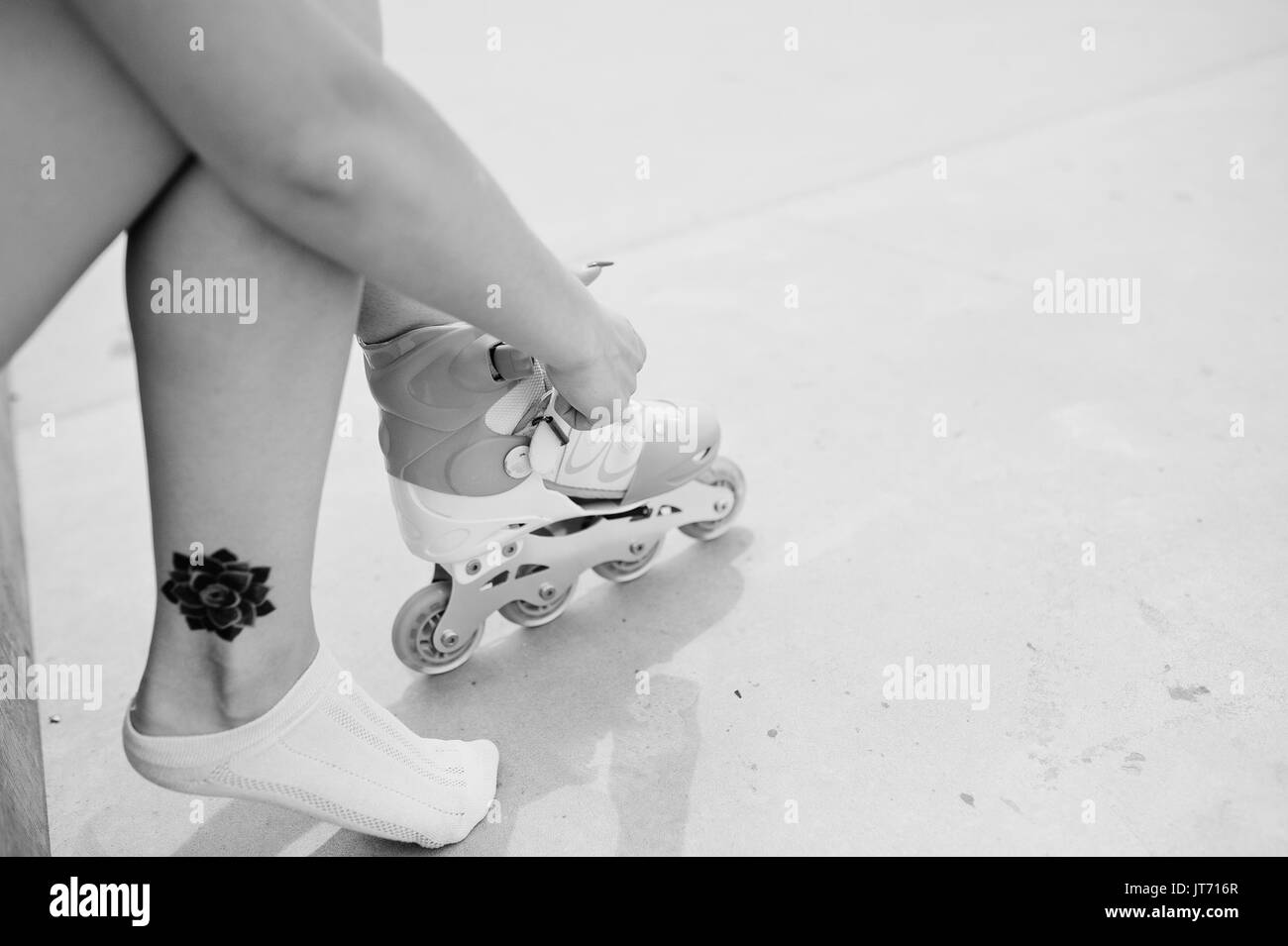 Giovane donna mettendo su pattini esterni. Foto in bianco e nero. Foto Stock