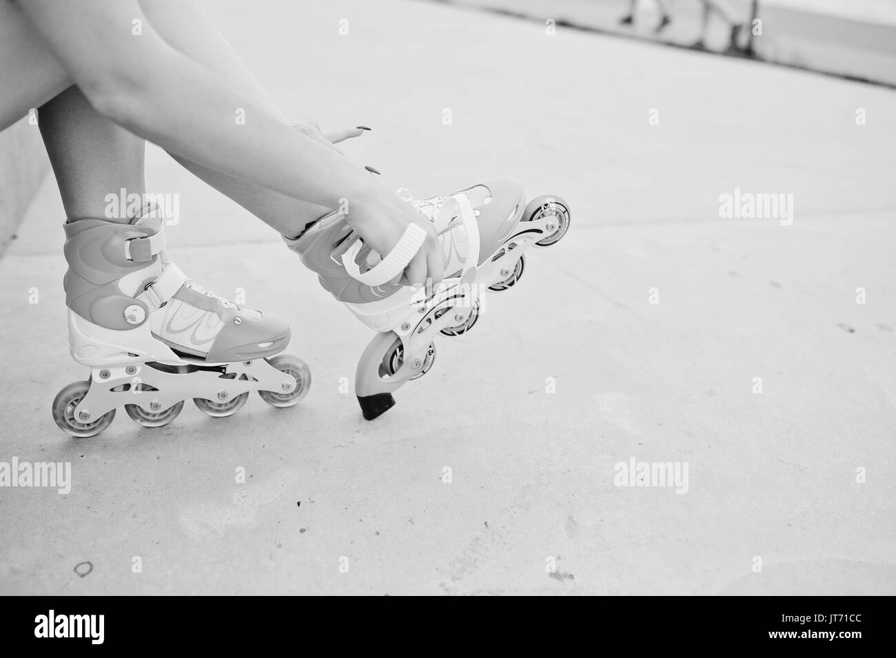 Giovane donna mettendo su pattini esterni. Foto in bianco e nero. Foto Stock