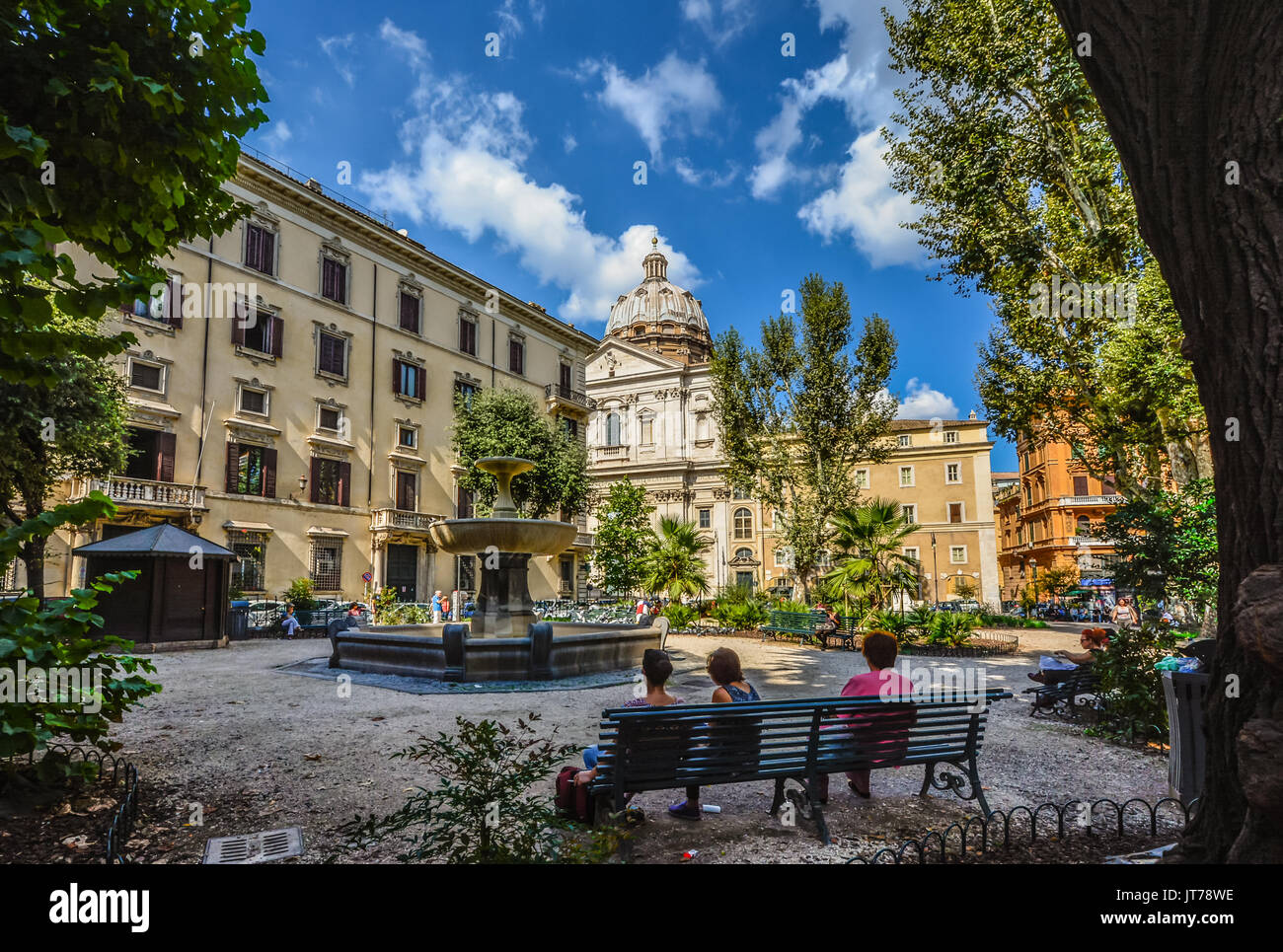 Piccola piazza a Roma Italia come signore potrete rilassarvi su una panchina nel parco all'ombra con cupola di una chiesa in background in una giornata di sole Foto Stock