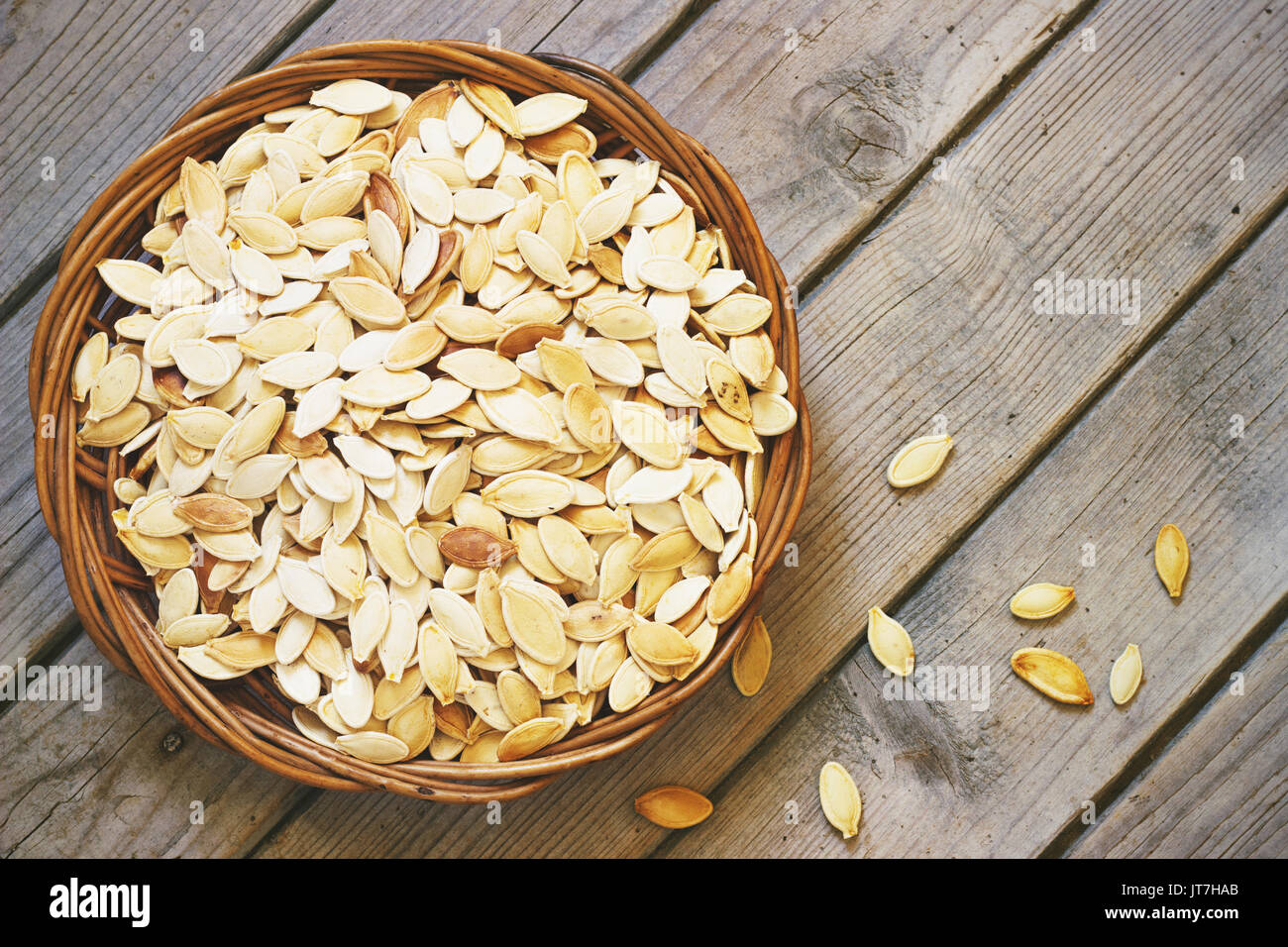 Salati semi di zucca su un rustico sfondo di legno in un cesto di vimini Foto Stock