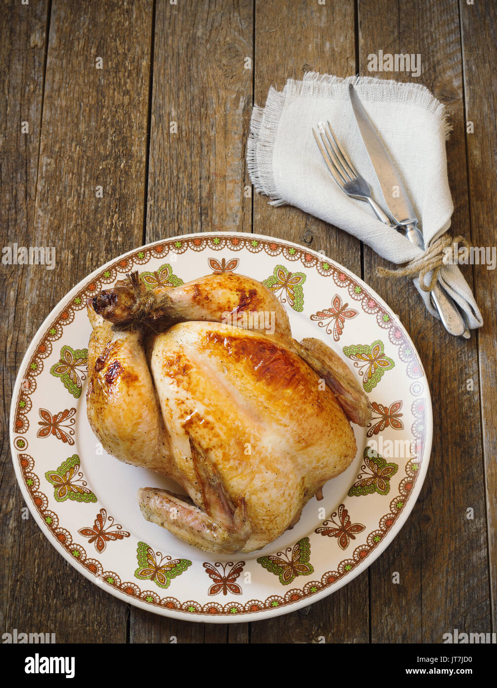 Tutto il pollo arrosto con posate su un tavolo di legno tonificante Foto Stock