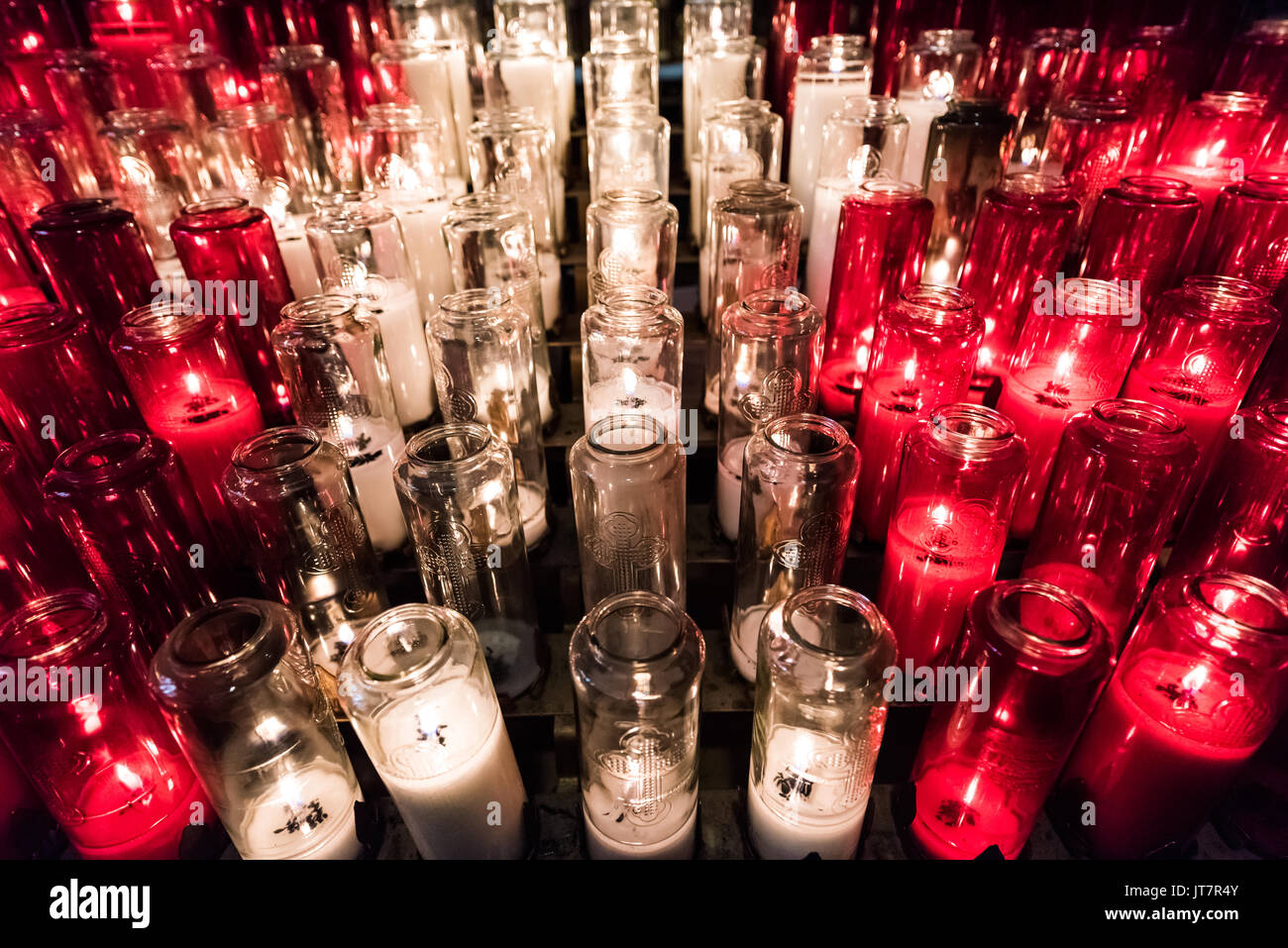 Il bianco e il rosso candele votive con fiamma gialla nella chiesa Foto Stock