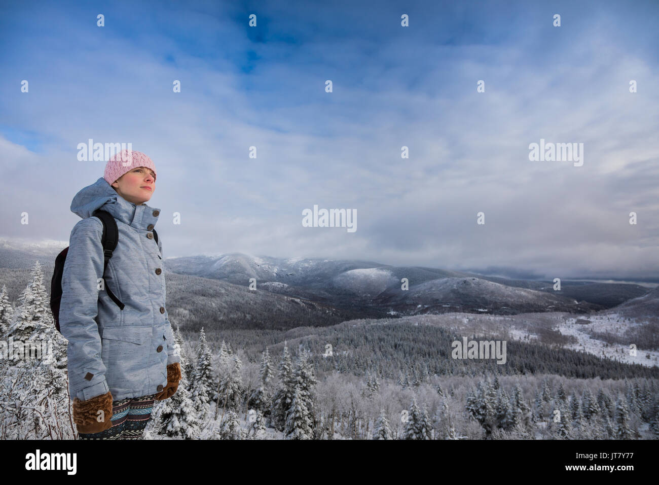Giovane donna soddisfatti guardando la vista dalla cima di una montagna in inverno Foto Stock