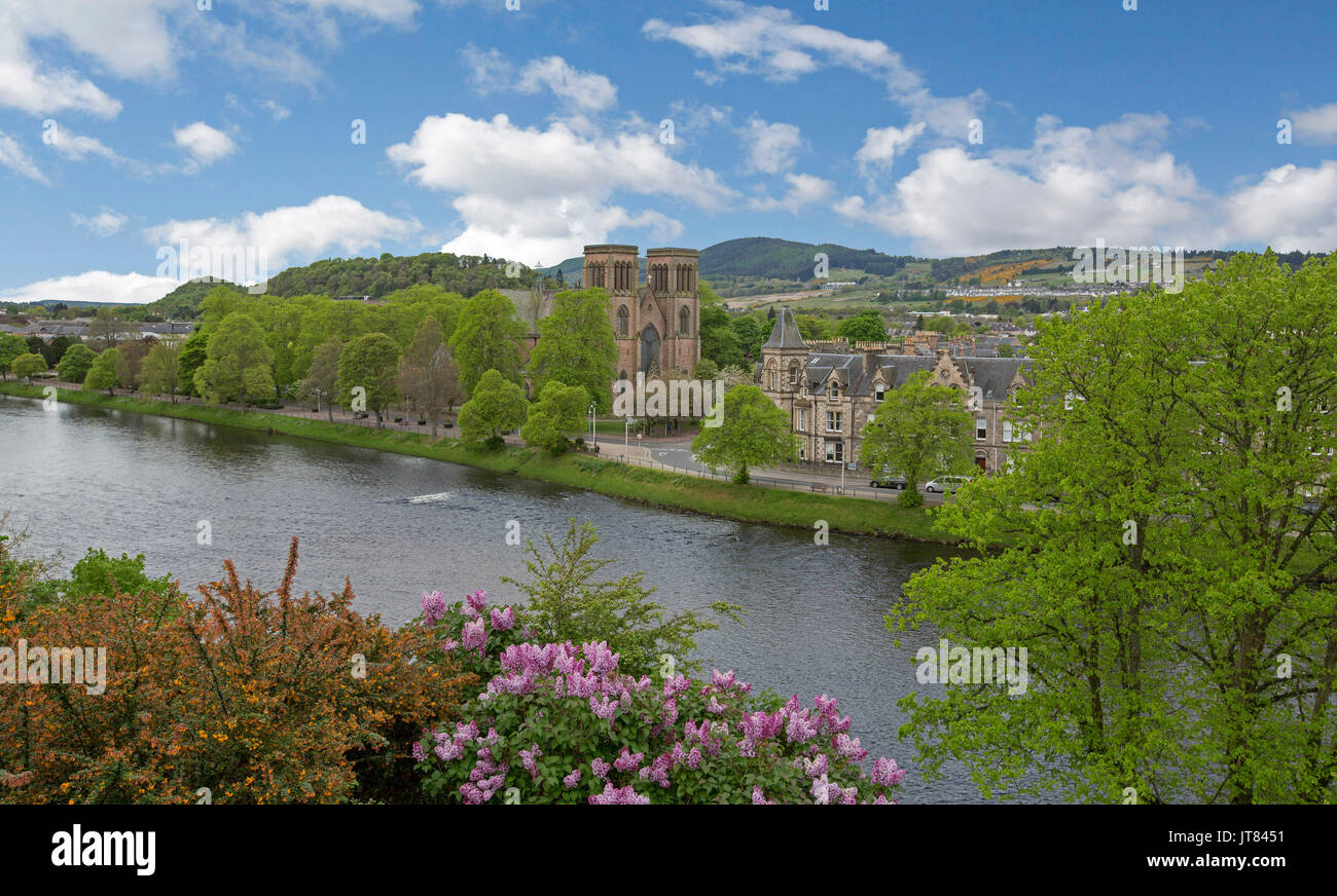 Città di Inverness con edifici storici, alberi e fiori confinante con il fiume Ness con le montagne sullo sfondo sotto il cielo blu in Scozia Foto Stock