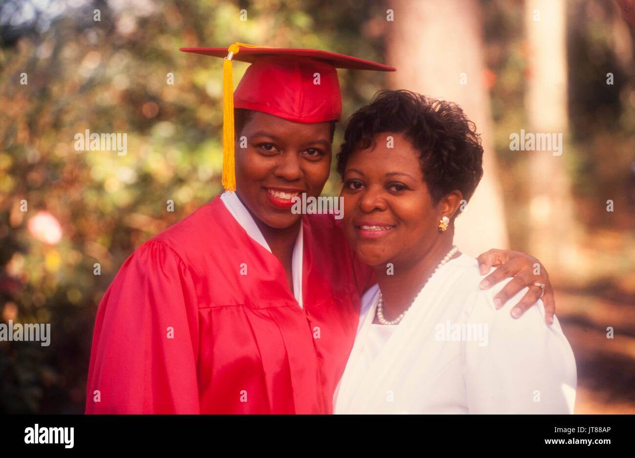 An African American graduate nel suo cappuccio rosso e camice con un oro tassel Foto Stock