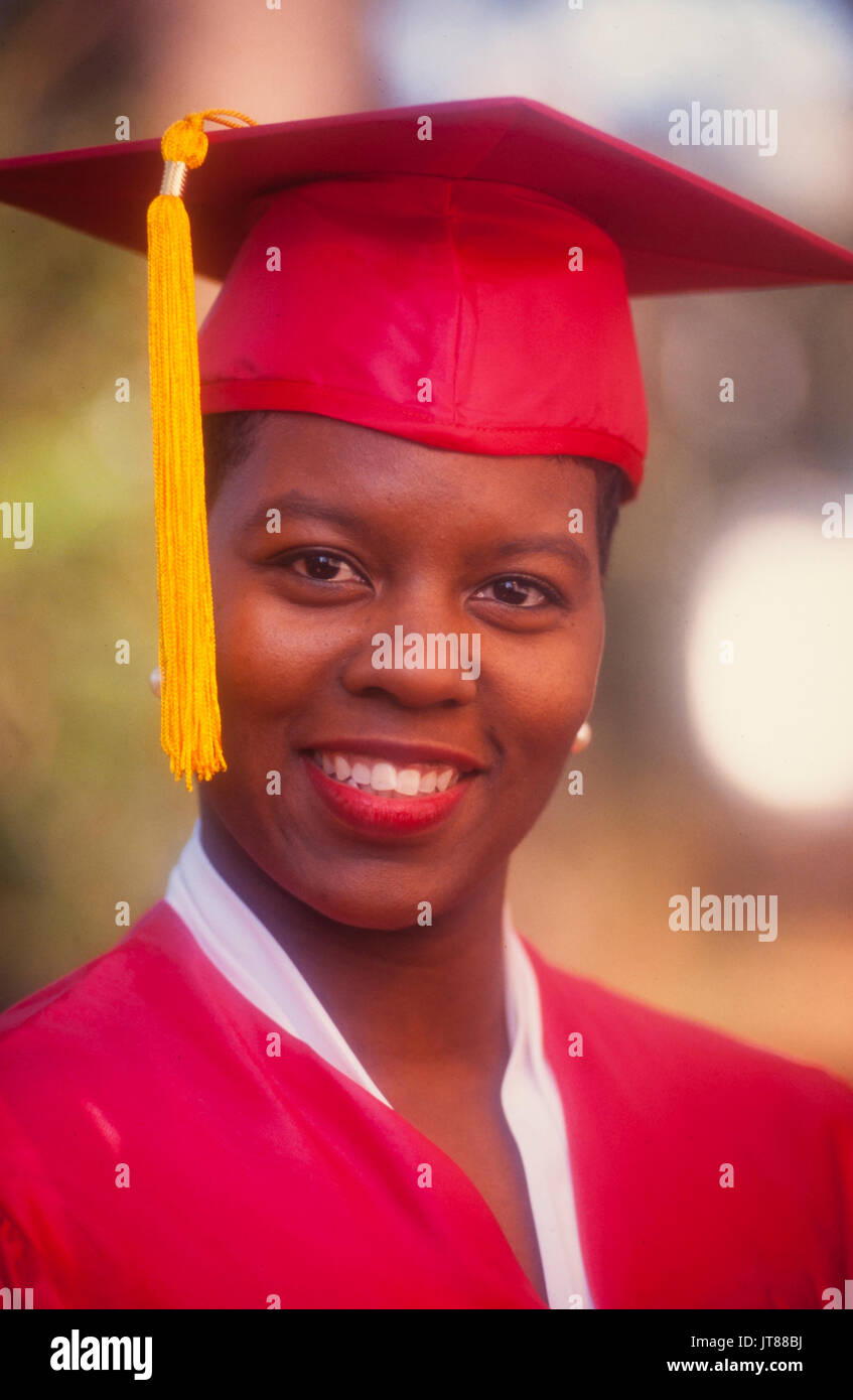 An African American graduate nel suo cappuccio rosso e camice con un oro tassel Foto Stock