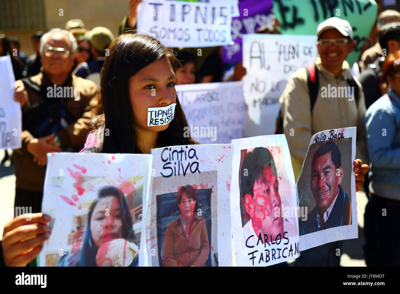 La Paz, Bolivia, 8 agosto 2017. Un manifestante mantiene coperti di sangue foto di governo figure a un incontro per manifestare la propria opposizione ai piani del governo di annullare la Legge 180, che è oggi in discussione al Senato. La legge è stata creata nel 2011 dopo le proteste di massa (che comprendeva un 2 mese marzo dalla regione di La Paz) da TIPNIS abitanti e molti altri contro governo controversi piani per la costruzione di una strada attraverso la regione senza consultazione Credito: James Brunker/Alamy Live News Foto Stock