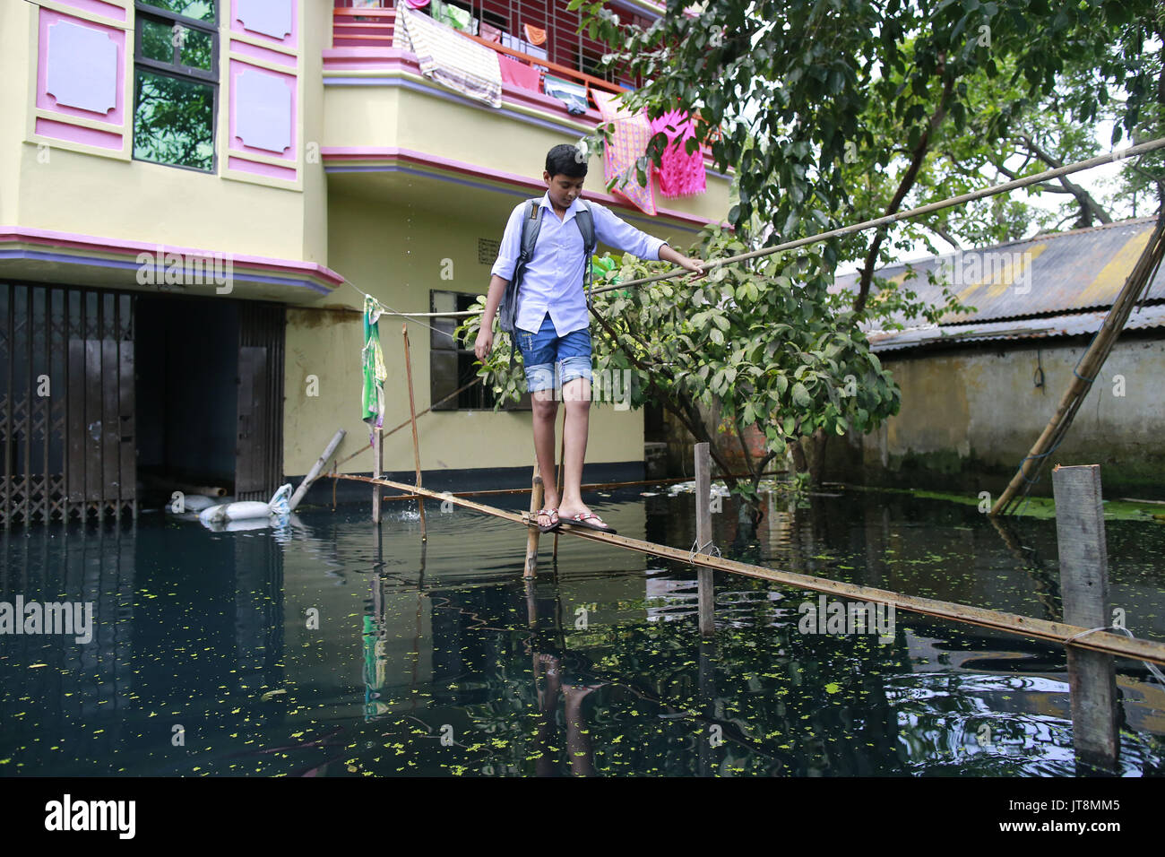 Dacca in Bangladesh. 8 Ago, 2017. Uno studente del Bangladesh si attraversa un ponte di fortuna fatta con ferro a Demra, a Dhaka, nel Bangladesh, 8 agosto 2017. La miscelazione di acqua piovana e rifiuti tossici prodotti dalle industrie ha girato acqua nel verde. Credito: Suvra Kanti Das/ZUMA filo/Alamy Live News Foto Stock