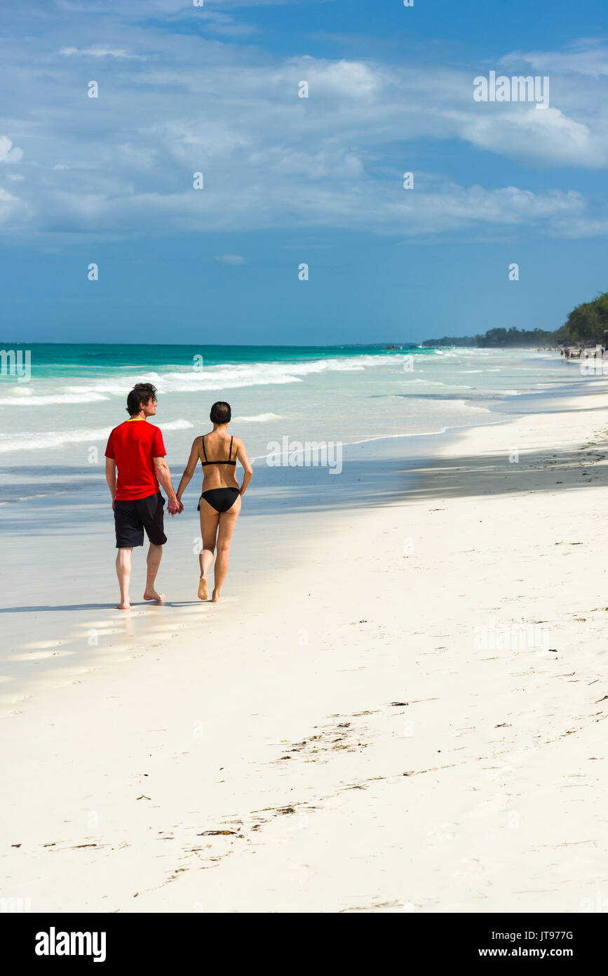Un giovane a piedi lungo il tropical spiaggia di sabbia bianca litorale in una giornata di sole, Diani, Kenya Foto Stock