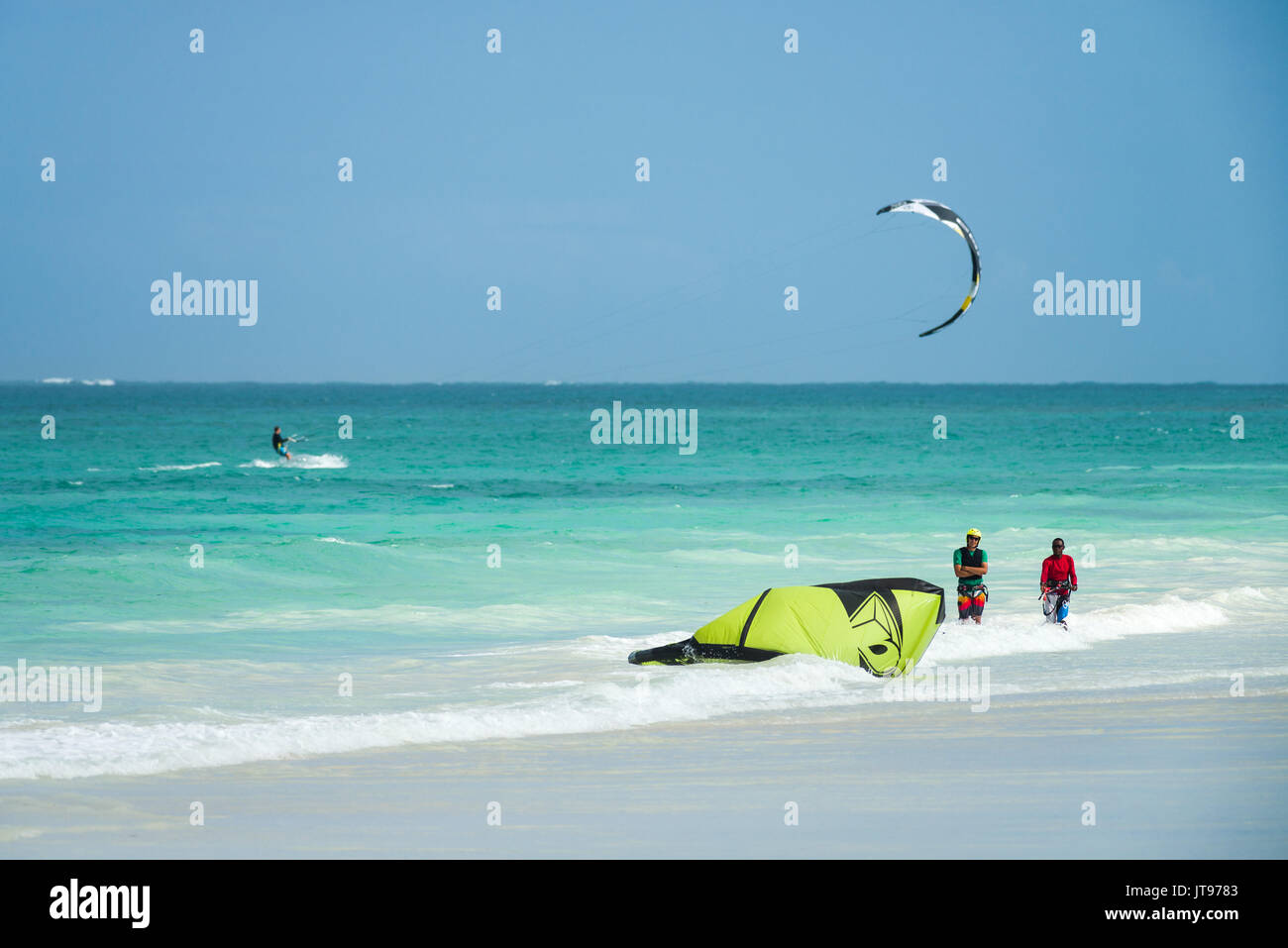 Kite surfers in acqua e alla spiaggia di sabbia bianca di costa, Diani, Kenya Foto Stock