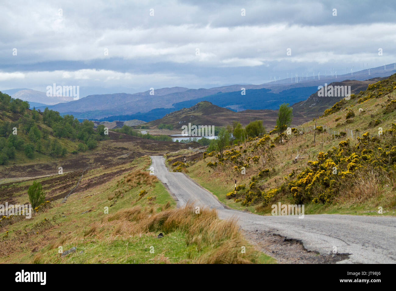 Paesaggio di montagna nelle highlands scozzesi tagliato da strada stretta che conduce al Loch Tarff e le montagne sull orizzonte sotto storia sky, Scozia Foto Stock