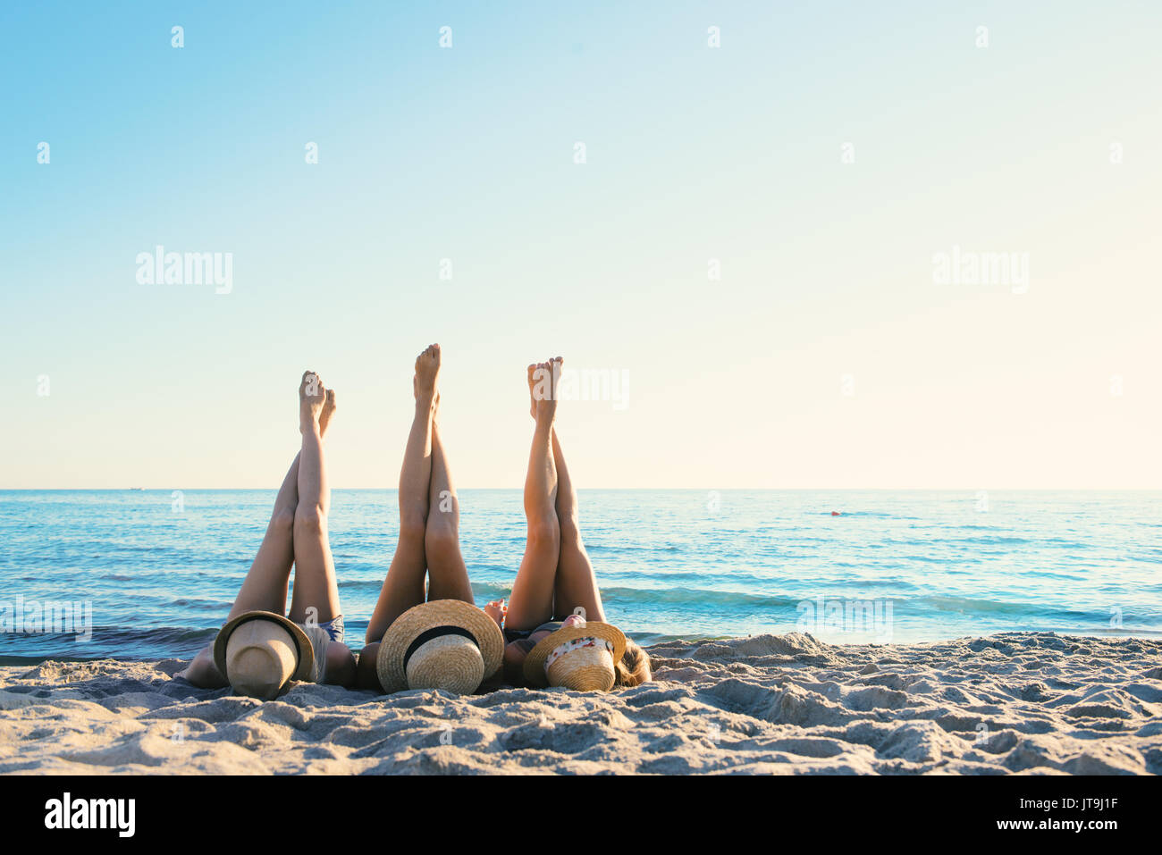 Gruppo di happy amici divertendosi a Ocean Beach con le gambe in alto Foto Stock