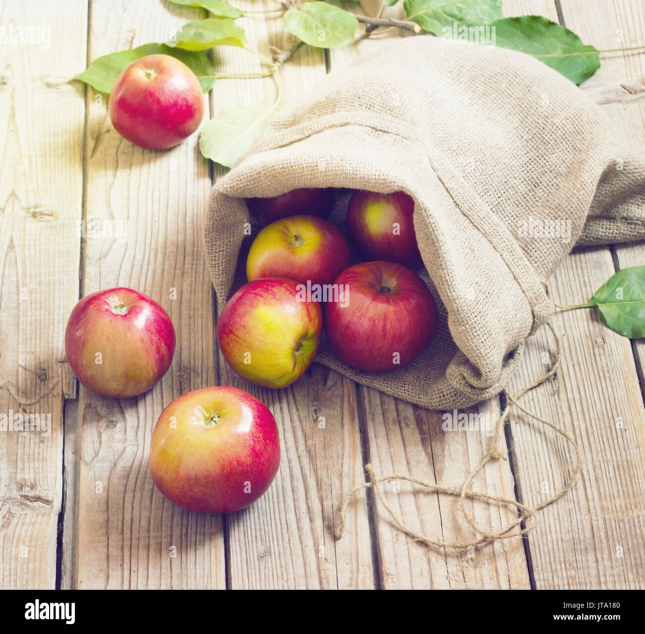 Mature mele rosse in un sacchetto sul vecchio legno tonificante di sfondo Foto Stock