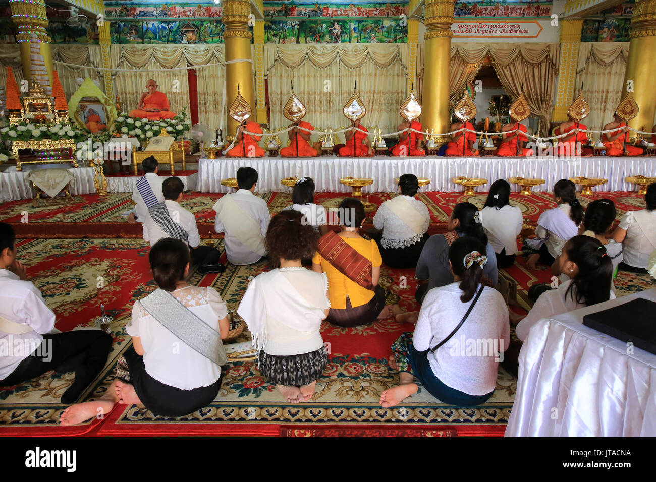 Seduti i monaci buddisti pregano in ricordo del defunto, Wat Ongs Teu Mahawihan (il Tempio del Buddha di pesanti), Vientiane, Laos, Indocina, Southeas Foto Stock