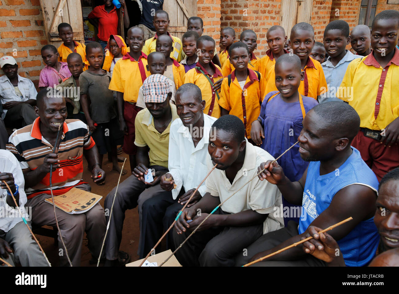 Gli abitanti di un villaggio ugandese di bere home-birra alla spina e scolari, Bweyale, Uganda, Africa Foto Stock