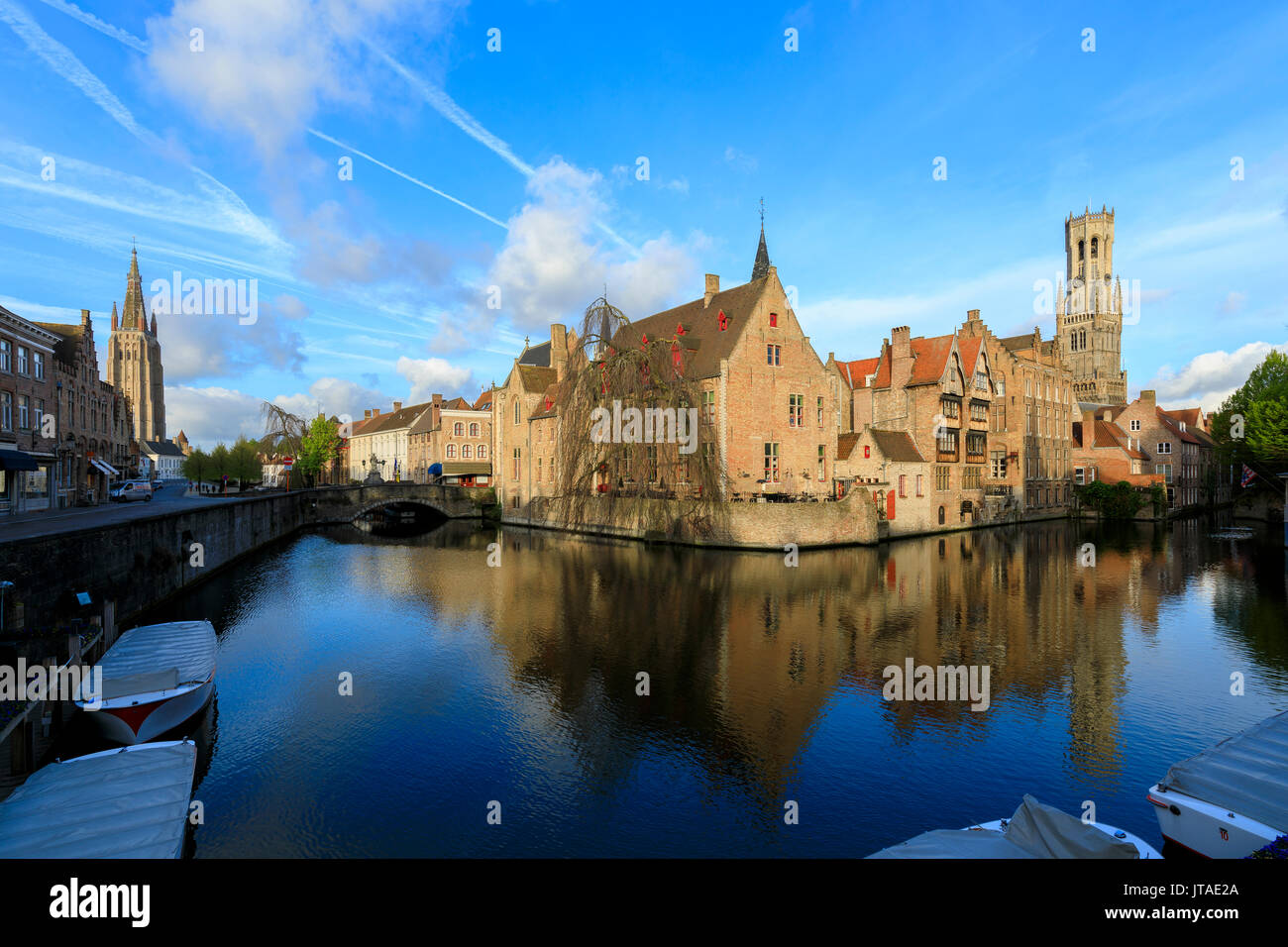 Prime luci dell'alba sulla torre campanaria e gli edifici storici si riflette in un tipico canale di Bruges, sito Patrimonio Mondiale dell'UNESCO, Fiandre Occidentali, Belgio, e Foto Stock
