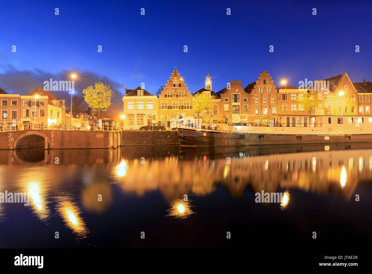 Le luci del tramonto sul case tipiche e il ponte si riflette in un canale del fiume Spaarne, Haarlem, Olanda Settentrionale, Paesi Bassi, Europa Foto Stock