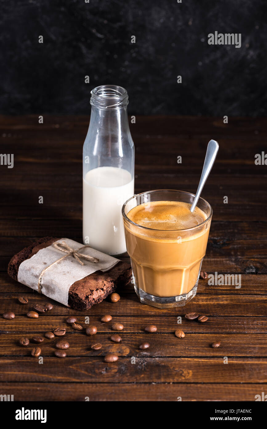 Caffè, latte in bottiglia di vetro e in casa brownie torta sul tavolo in legno Foto Stock