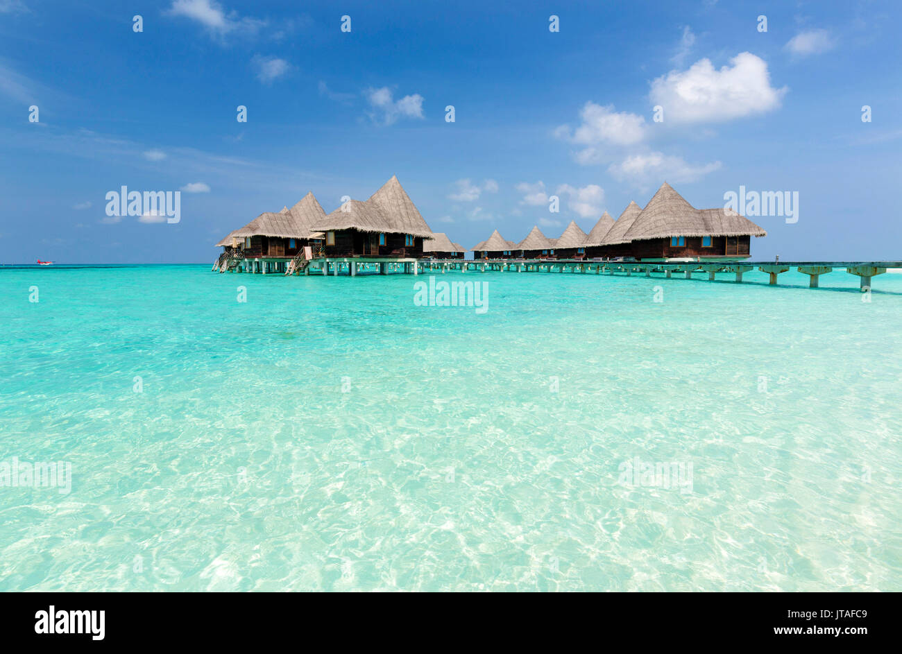 Il mare limpido e azzurro cielo e over-ville sull'acqua, Coco Palm Resort, Dhuni Kolhu, Baa Atoll, Repubblica delle Maldive, Oceano Indiano, Asia Foto Stock
