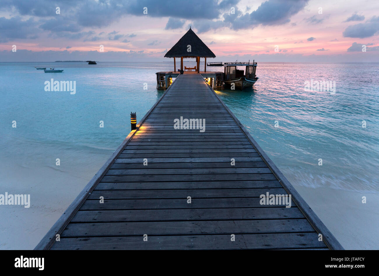 Pontile in legno e in barca al tramonto, Coco Palm Resort, Dhuni Kolhu, Baa Atoll, Repubblica delle Maldive, Oceano Indiano, Asia Foto Stock