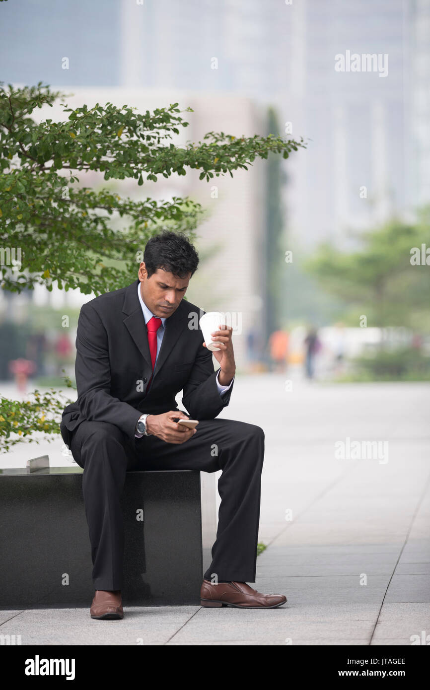 Indian business man con il suo smart phone all'aperto in città asiatiche. Foto Stock