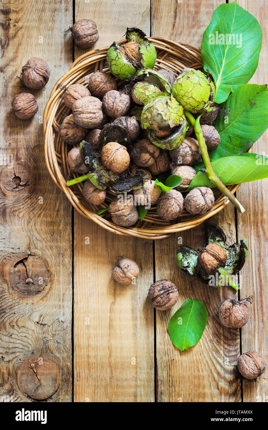 Le noci in lolla di verde con foglie su un sfondo di legno Foto Stock