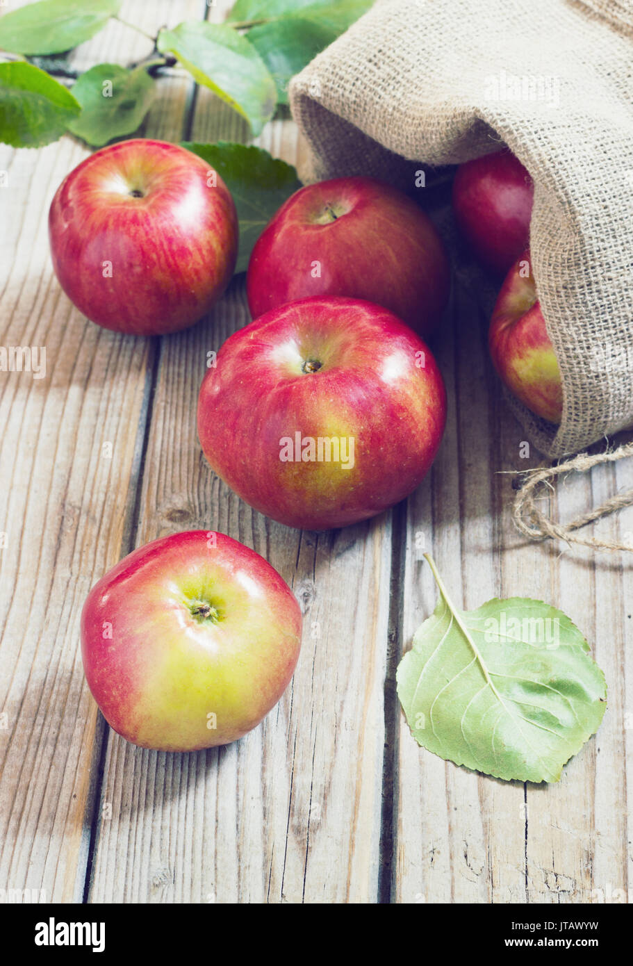 Mature mele rosse in un sacchetto sul vecchio legno tonificante di sfondo Foto Stock