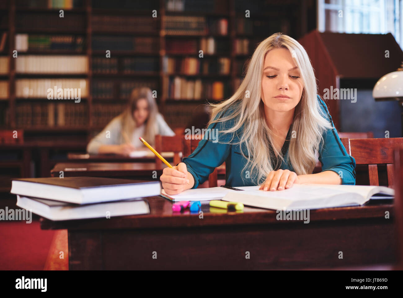 Donna che lavorano alla scrivania prendendo appunti Foto Stock