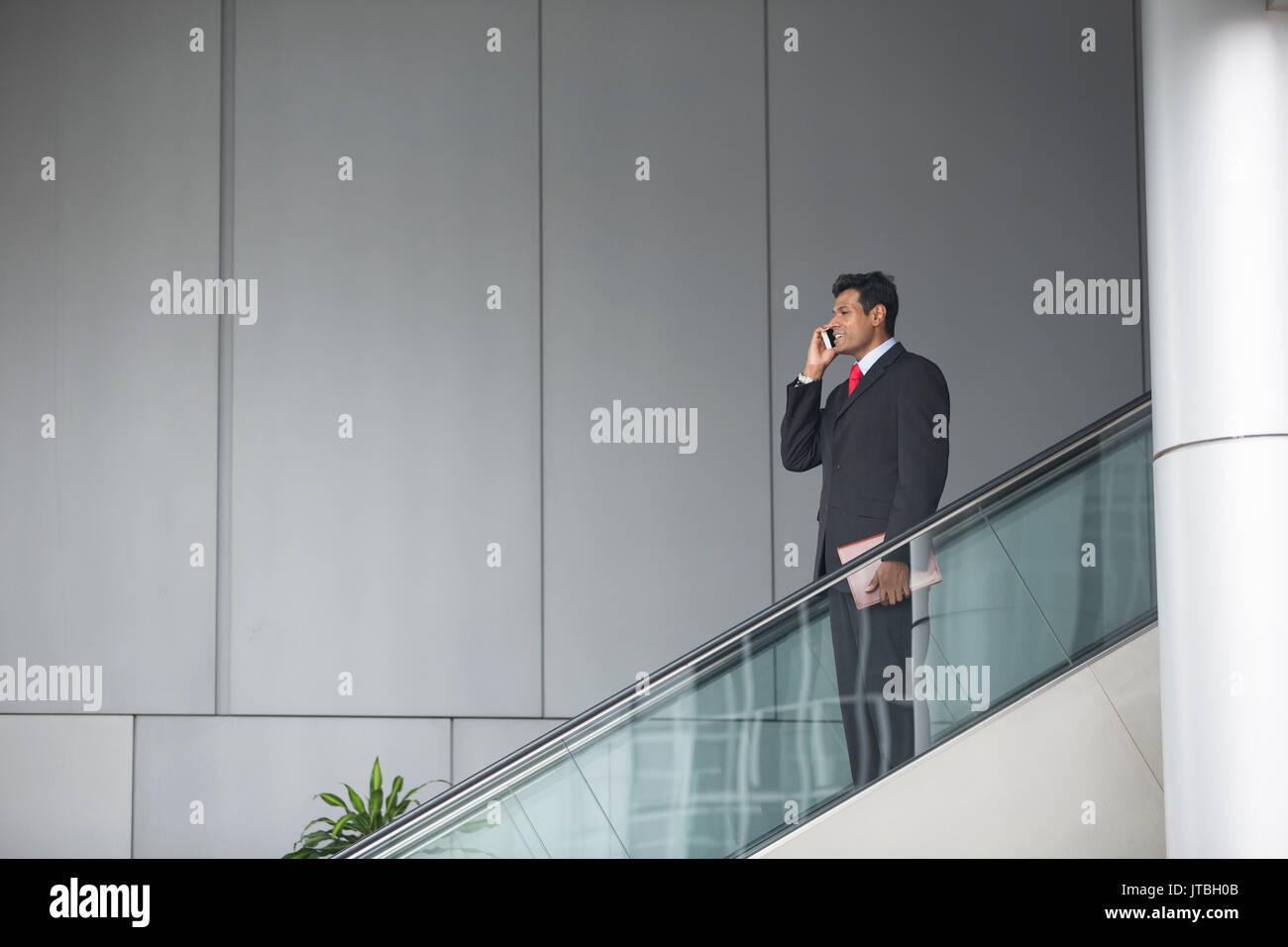 Ritratto di un fiducioso commerciante indiano in piedi su una scala mobile nella città. Foto Stock