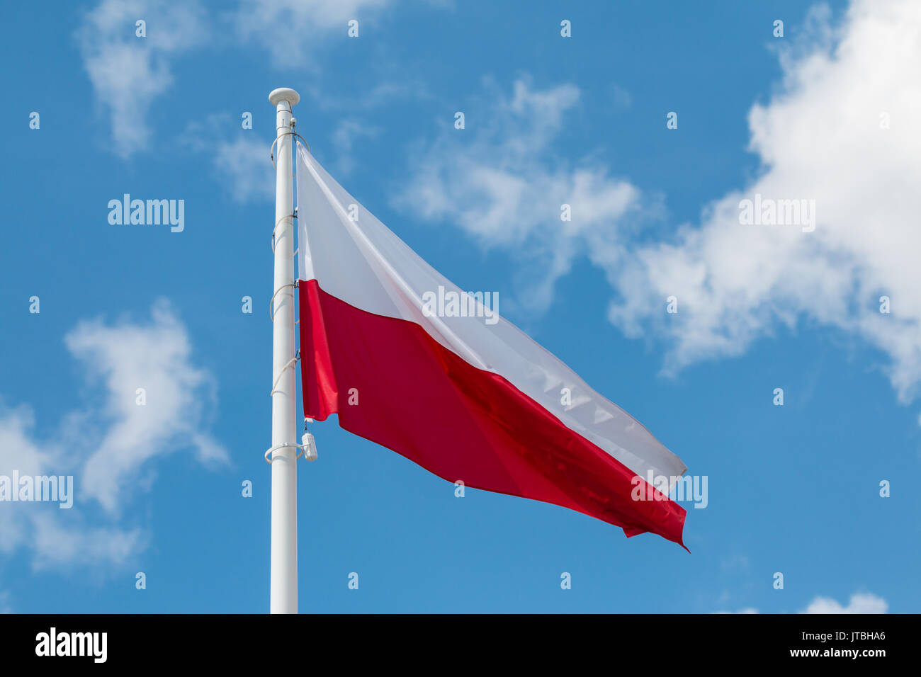 Sventola bandiera nazionale della Polonia su un pennone, colori nazionali della Polonia. Foto Stock