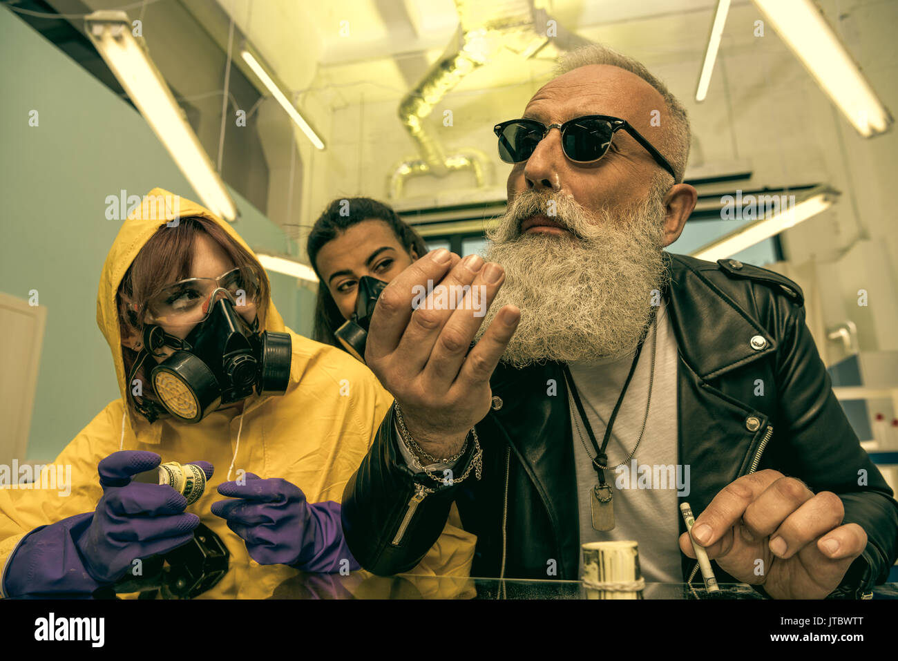 Capelli grigi uomo con barba prendendo farmaci con donne in equipaggiamento protettivo personale, concetto di droga Foto Stock