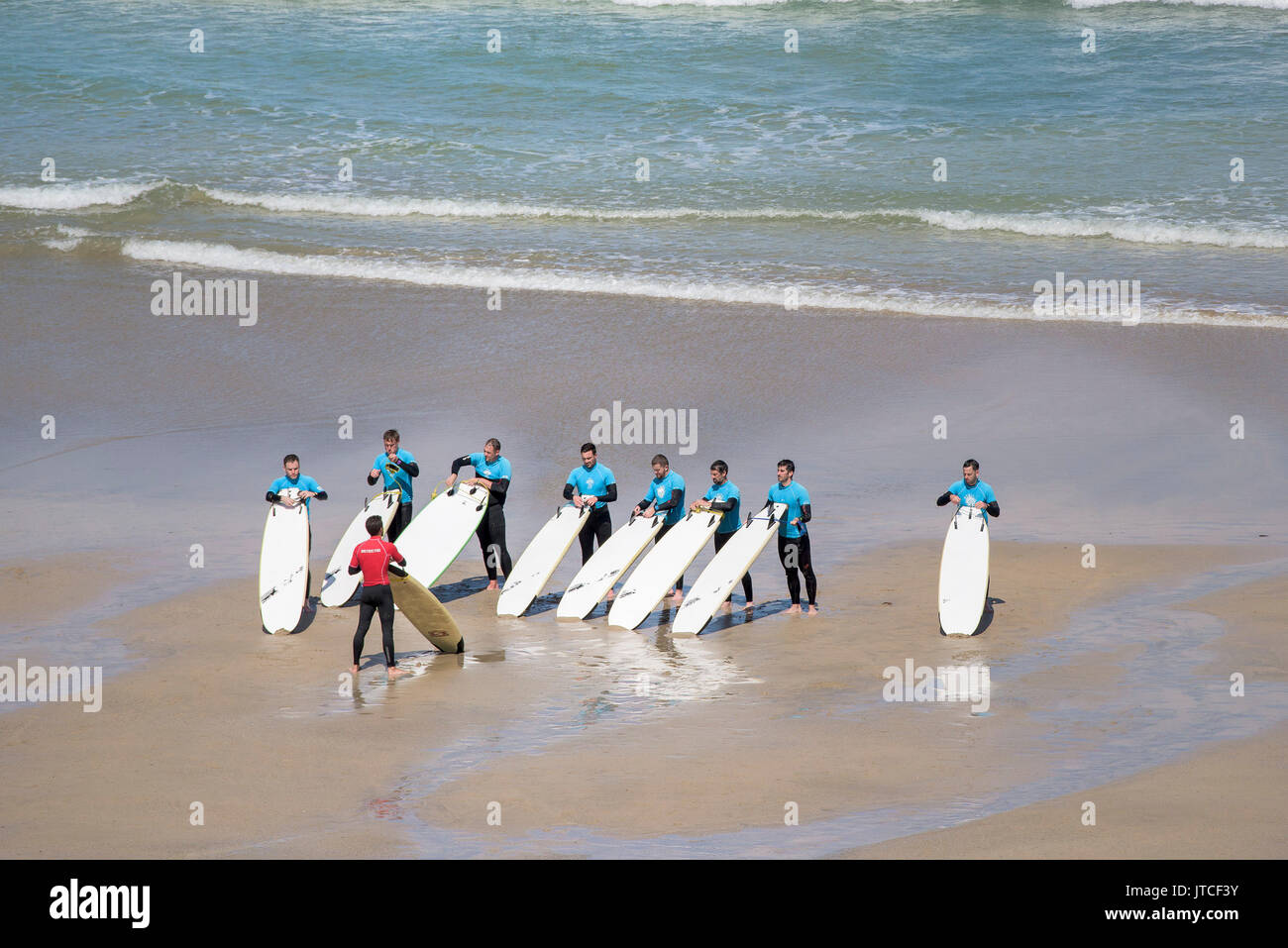 Una scuola di surf istruttore e i suoi allievi su Great Western Beach in Newquay, Cornwall. Foto Stock