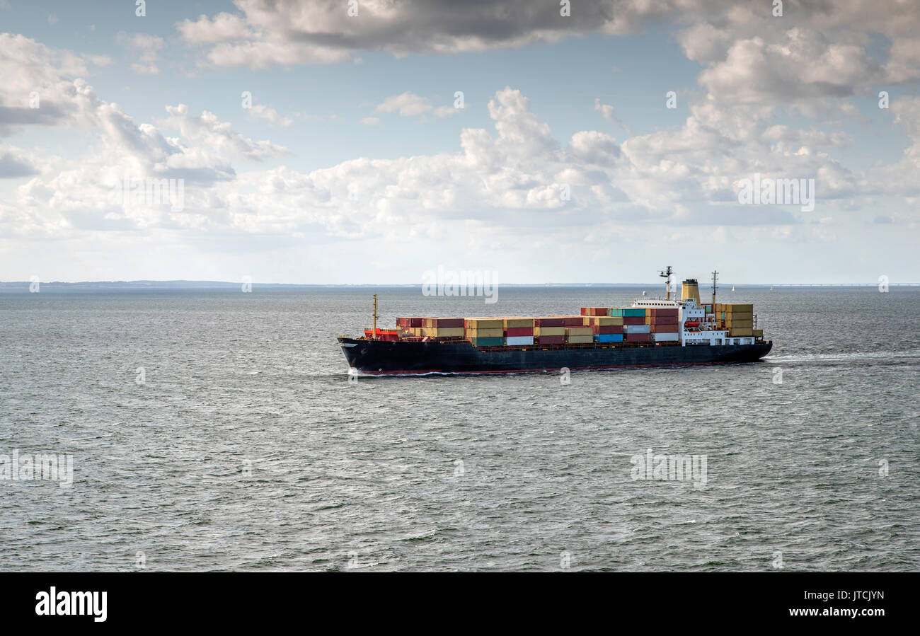 Contenitore nave in mare con il ponte per la Danimarca sullo sfondo Foto Stock